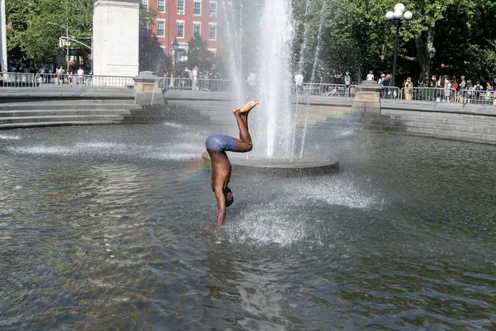 A man enjoys cool water in Washington Square fountain during heat wave when temperature reach 93 degrees Fahrenheit (34 degrees Celsius). Heat will continue to hit city for the next few days.